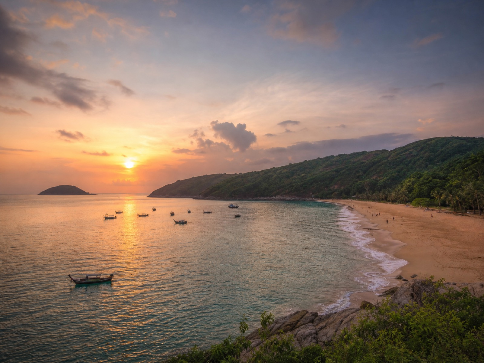 Nai Harn Beach at sunset with warm sky and a curved bay